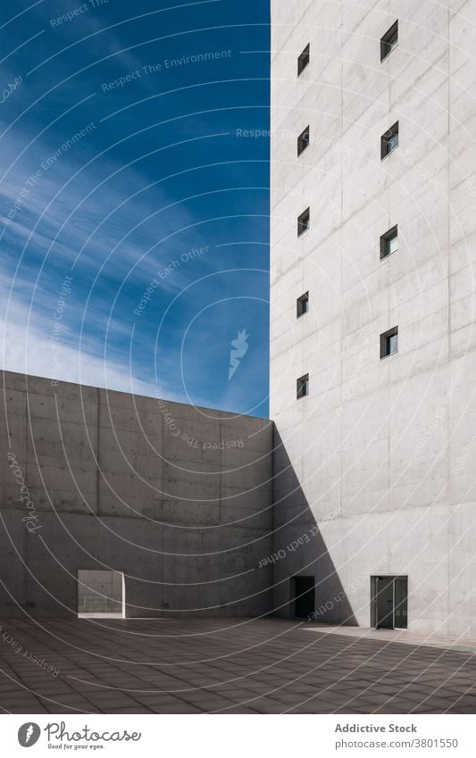 Exterior of tall concrete building in minimalist style architecture brutalist facade severe gray monolithic rough design exterior barrier gate tiny window