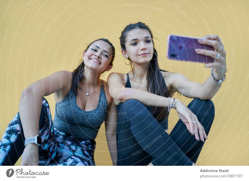 Positive women sitting on floor and taking selfie on smartphone content positive gadget friend cheerful using moment modern young mobile social media browsing