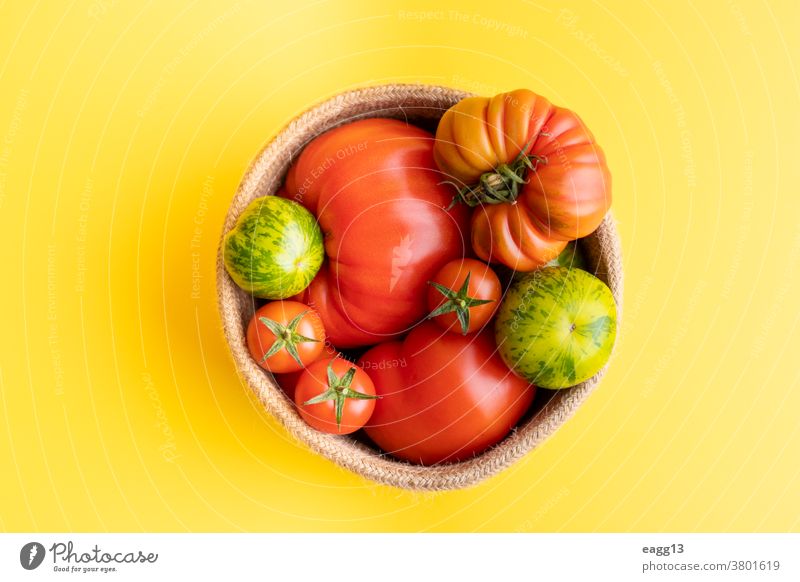 Basket with a variety of tomatoes, including: Cherry, Heirloom and Zebra on a yellow background abundance baskets cherry colourful delicious different farming