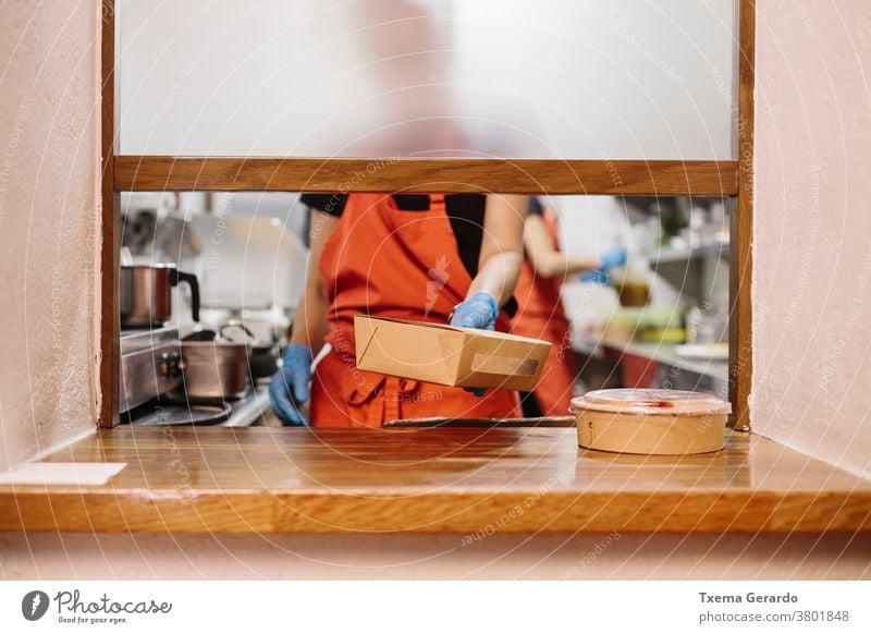 Cooks in a restaurant preparing takeaway food. The containers used are compostable. cook kitchen salad window chef vegetable cooking catering woman professional