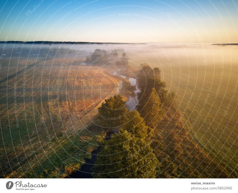 Small river with trees in meadow and field. Colorful misty morning dawn fog nature autumn sunrise water forest sunlight landscape background fall sunset season