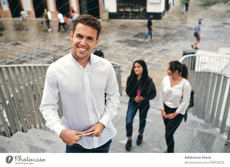 Smiling student with tablet behind diverse partners friend internet smile online conversation stair street using device colleague watching trendy friendship