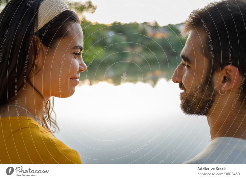 Happy ethnic couple smiling and looking at each other near lake romantic date love together rest pond park smile relationship relax positive happy boyfriend