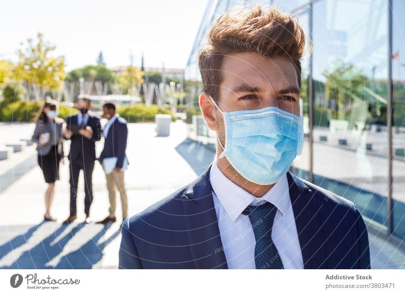 Thoughtful young male entrepreneur standing on street in sunlight man serious thoughtful businessman formal work new normal colleague discuss communicate