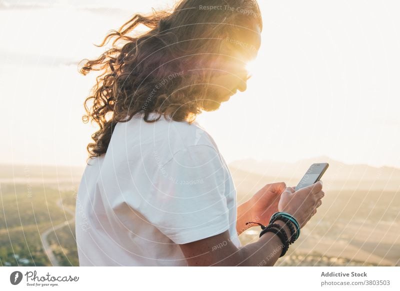 Crop positive man using smartphone against spacious green valley scenic calm viewpoint nature gadget hilltop wanderlust travel amazing traveler device grassy