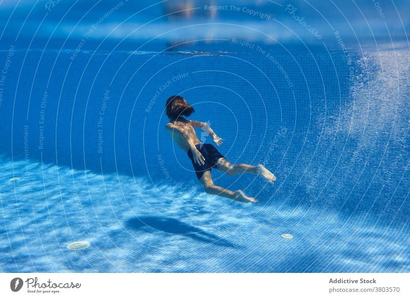 Teenage boy diving into pool water teenage energy dive swim active underwater activity carefree playful splash aqua resort plunge enjoy relax delight bubble