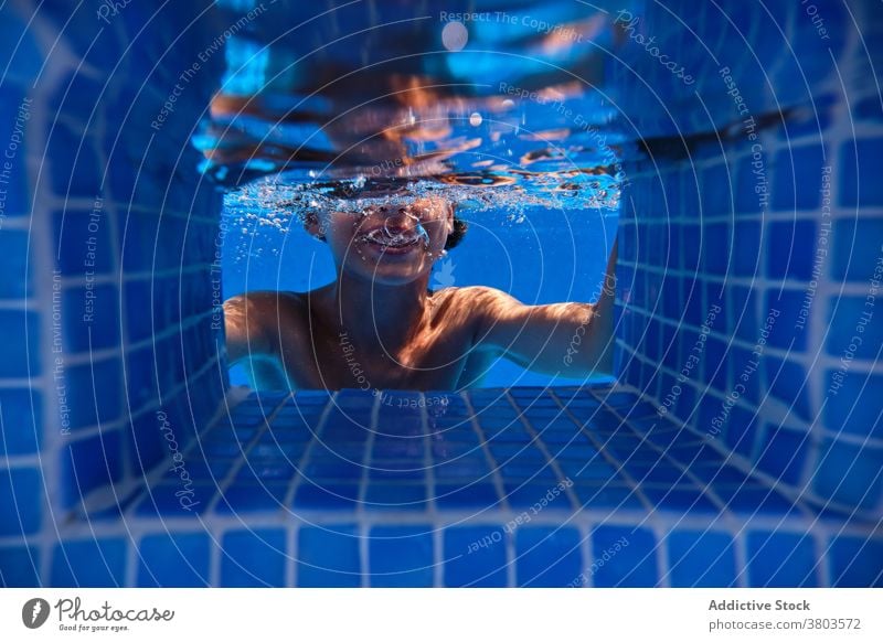 Joyful boy diving into pool water teenage dive bubble cheerful underwater activity smile fun carefree playful splash aqua active resort enjoy swim relax laugh