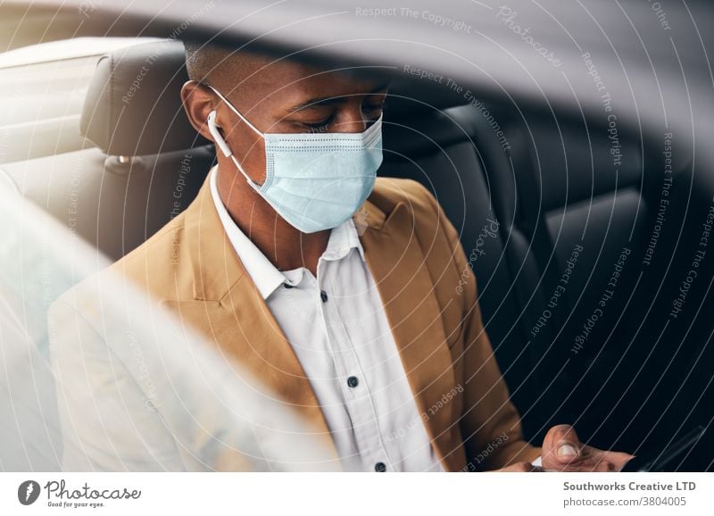 Young Businessman Wearing Mask Checking Mobile Phone In Back Of Taxi During Health Pandemic business businessman taxi face mask face covering wearing ppe cab