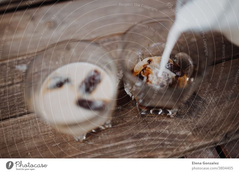 Pour milk in delicious coffee ice cubes on wood table Coffee freeze Milk wooden drink brewed beverage glass iced coffee cafe aroma frappe mocha brown black