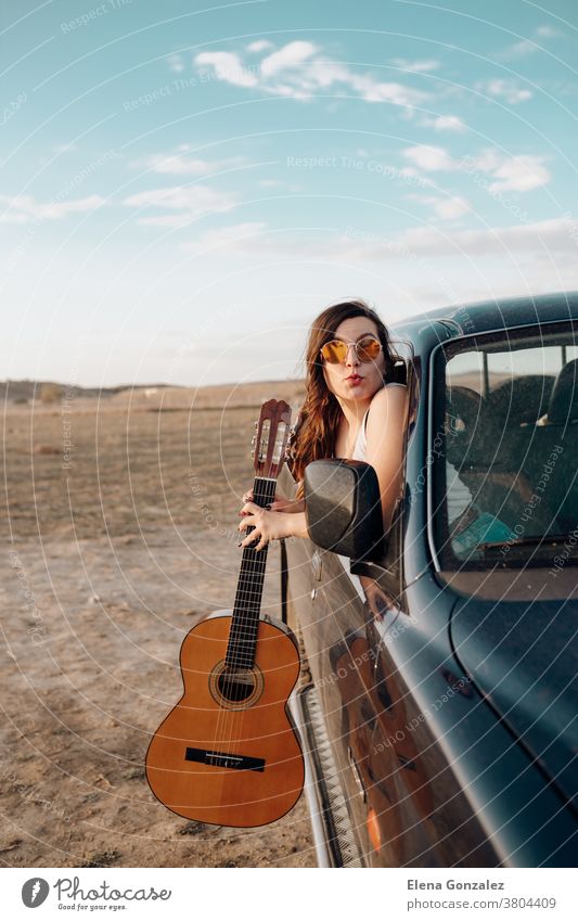 Young traveler woman having fun with the guitar in the jeep 4x4 car making a wanderlust vacation at sunset female trip people young vintage beautiful lifestyle