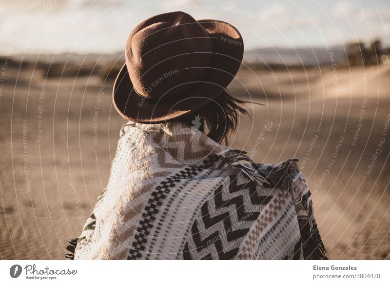 young woman from backwards with scarf and hat in the desert at sunset bandana windy windy day outdoor alone dune girl walk female lady arab hot attractive