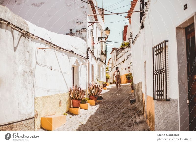 young fashionable brunette woman walking down a street one in Elvas, Portugal Street White street Yellow streel Summer Summer day Pots flowers pots colorful