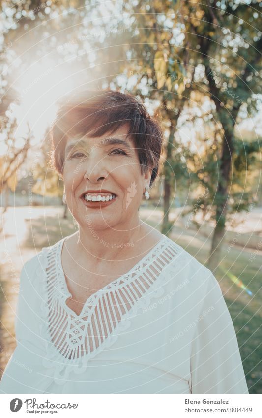 Close up portrait of a hispanic senior woman in the park at sunset looking casual mature mid age close up leisure lovely 50s Hispanic female countryside