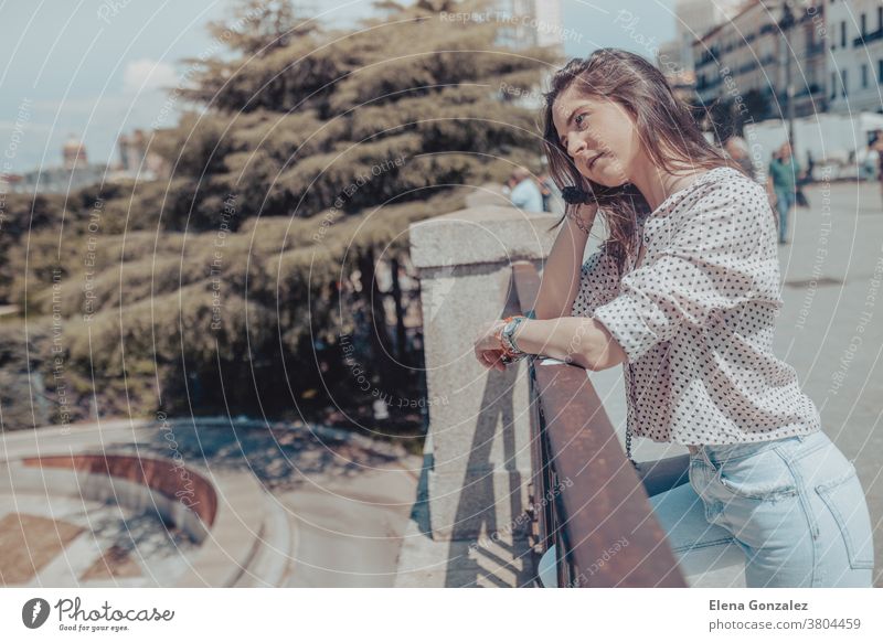 Beautiful young woman resting on a railing near Royal Palace of Madrid, Spain Tourist Young Woman Girl Fashion fashionable bag handbag Purse railings serious