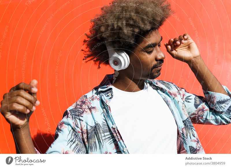 Stylish dreamy black man in modern headset on street headphones stylish listen music eyes closed masculine afro hairstyle african american ornament wear