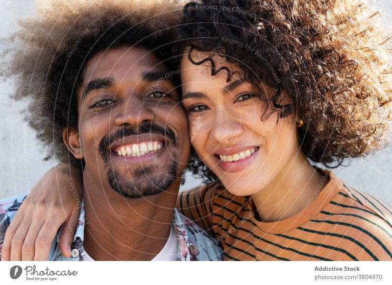 Happy young ethnic couple hugging and smiling at camera smile cuddle cheerful happy love relationship together embrace portrait enjoy affection sunny day