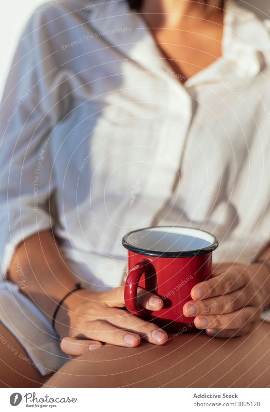 Anonymous young woman drinking coffee in bed morning happy sensual comfort allure cozy joy female white shirt body home beverage sunny relax rest positive