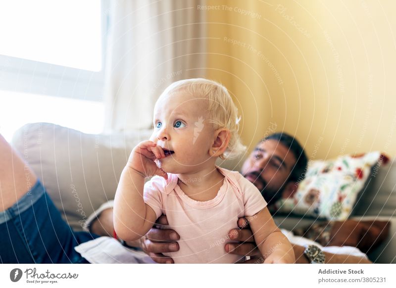 Cheerful dad playing with infant on sofa man baby love happy laugh together relationship father bonding affection couch home cute adult babyhood fatherhood