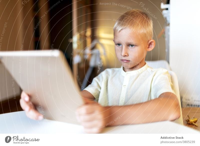 Focused boy watching films on tablet browsing kid child smart leisure serious concentrate online blond internet gadget device surfing connection modern focus