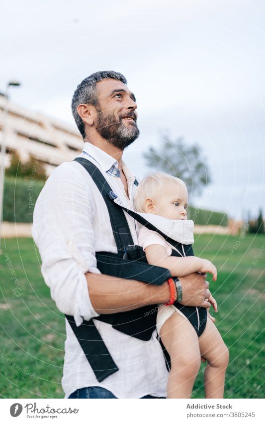 Father carrying son in sling man father infant innocent positive parenthood adorable stroll park male together beard lifestyle enjoy toothy smile leisure summer