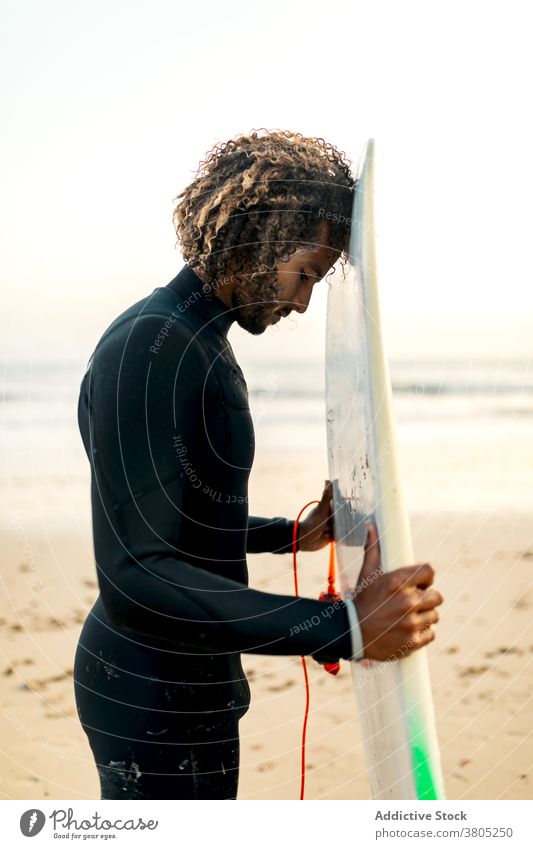 Pensive surfer holding skimboard man sunset seashore freedom tropical thoughtful water sports male resort ethnic pensive ocean beach summer swimsuit guy