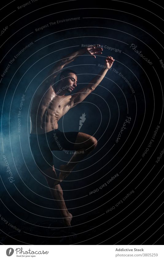 Sporty dancer training in dark room man arm raised motion perform rehearsal energy expressive muscular neon male shirtless sporty practice flexible slim