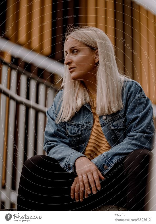 Junge blonde Frau sitzt auf der Treppe im urbanen Raum jeansjacke lange haare lifestyle portrait hübsch schön woman erholung selbstbewusst stadt innenstadt