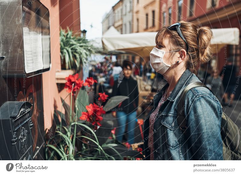 Young woman standing in a street downtown looking to the side wearing the face mask to avoid virus infection care caucasian contagious corona coronavirus cover