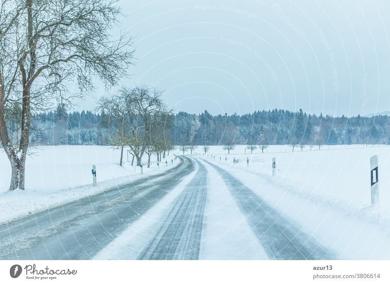 Lonely slippery icy winter road traffic with white snowy track. The street track is slick frozen. High dangerous risk of accident through blizzard snowstorm and severe christmas time season weather