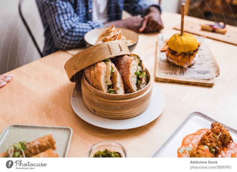 Unrecognizable man at table with delicious vegetarian sandwiches fast food lunch dinner menu meal restaurant naked bread cheese parsley hamburger tasty vegan