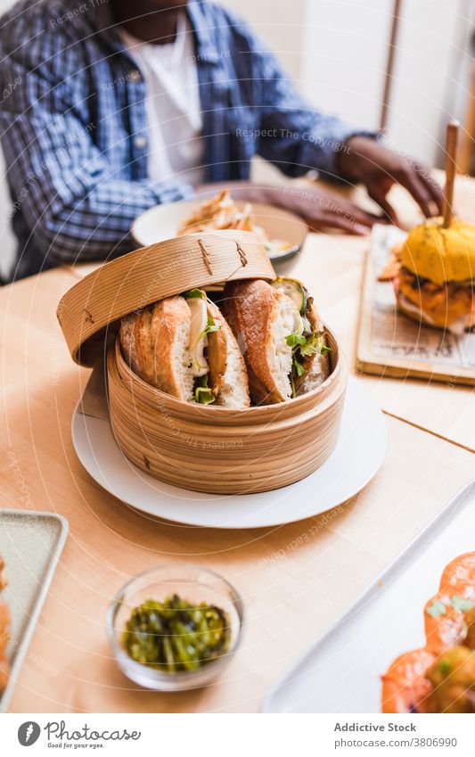 Unrecognizable man at table with delicious vegetarian sandwiches fast food lunch dinner menu meal restaurant naked bread cheese parsley hamburger tasty vegan