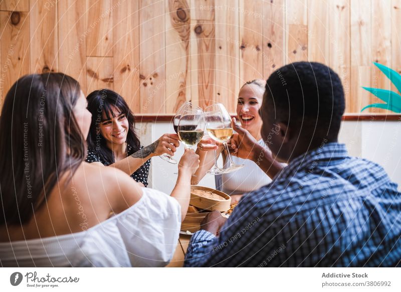 Happy diverse friends clinking glasses in cafe toast cheers drink wine dine cafeteria dinner cheerful celebrate positive tasty food friendly meet delicious