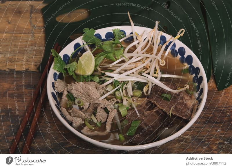 Bowl of tasty Vietnamese soup with beef on table pho vietnamese food bean sprout bowl tradition serve fresh parsley green onion lime piece meal dish vegetable