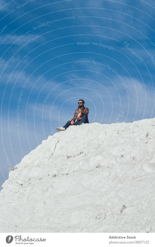 Anonymous man relaxing on chalk cliff in England nature traveler rest recreation hike activity holiday vacation male young beard casual trendy extreme