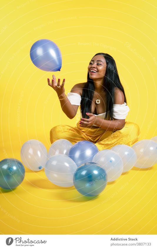 Cheerful young African American female playing with balloons in studio woman happy cheerful joy style model smile fashion playful positive optimist ethnic black