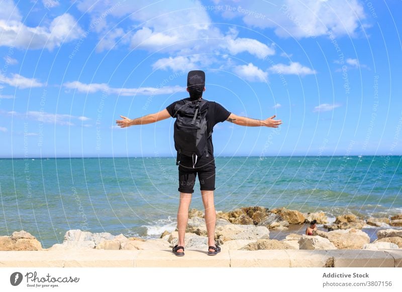 Male traveler enjoying seascape under sky during summer trip tourist backpack dreamy freedom man ocean nature blue sky cloudy apparel modern mindfulness