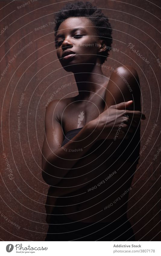 Alluring black woman standing in dark studio model seductive allure grace slender feminine temptation sensual vogue appearance fit beautiful attractive