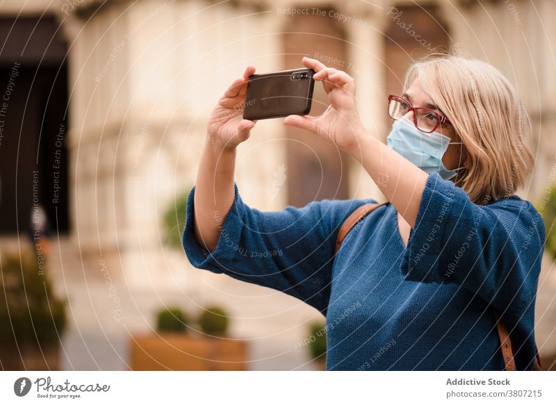 Woman in protective mask taking photos of old buildings traveler take photo town coronavirus smartphone woman architecture sightseeing visit covid 19 covid19