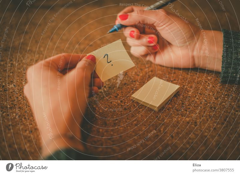 Female hands holding a Post-It with a question mark in it Question mark insecurity working life uncreative Disorientated Puzzle Perplexed Concern