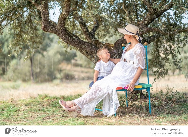 Pregnant woman spending time with her little son in the nature pregnant pregnancy mother family playing showing toddler boy baby expecting belly girl summer