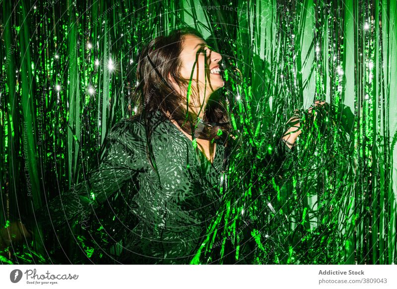 Cheerful woman playing with green tinsel party stripe having fun playful foil color vibrant female shiny dress festive happy cheerful delight enjoy trendy