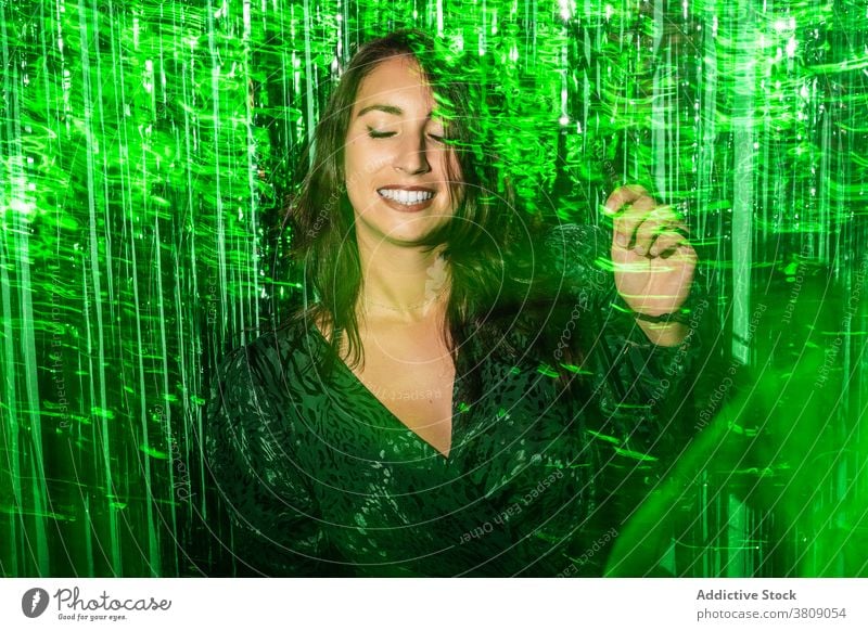 Cheerful woman playing with green tinsel party stripe having fun playful foil color vibrant female shiny dress festive happy cheerful delight enjoy trendy