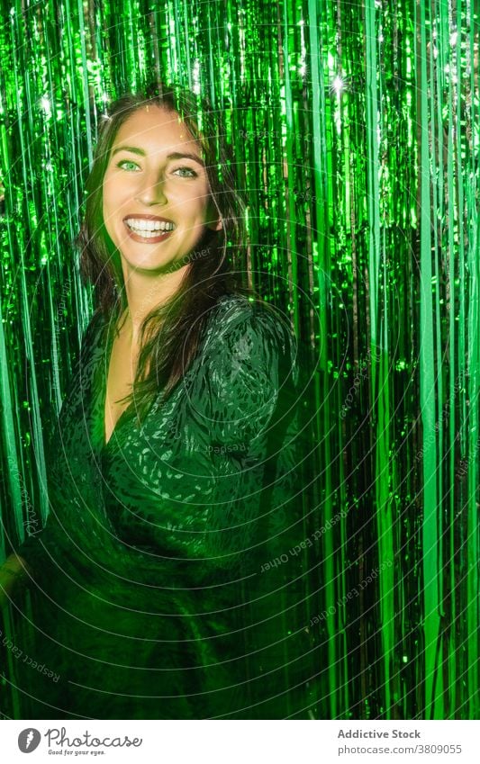 Cheerful woman playing with green tinsel party stripe having fun playful foil color vibrant female shiny dress festive happy cheerful delight enjoy trendy