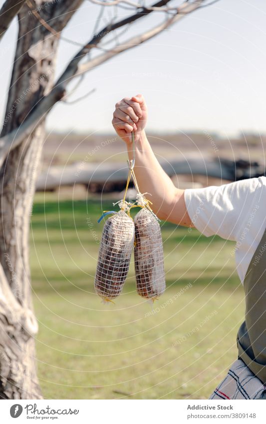 Crop man with homemade sausages in village countryside raw delicious natural food meat rustic male yard rural yummy fresh daytime sunny summer tasty stand meal