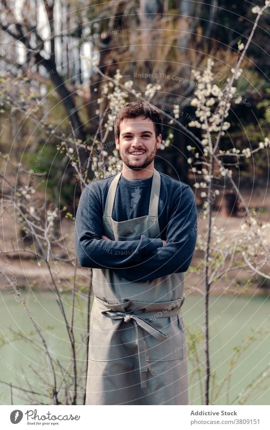 Smiling farmer in village on sunny day countryside man apron nature cheerful smile farmland rustic male positive happy season environment optimist joy