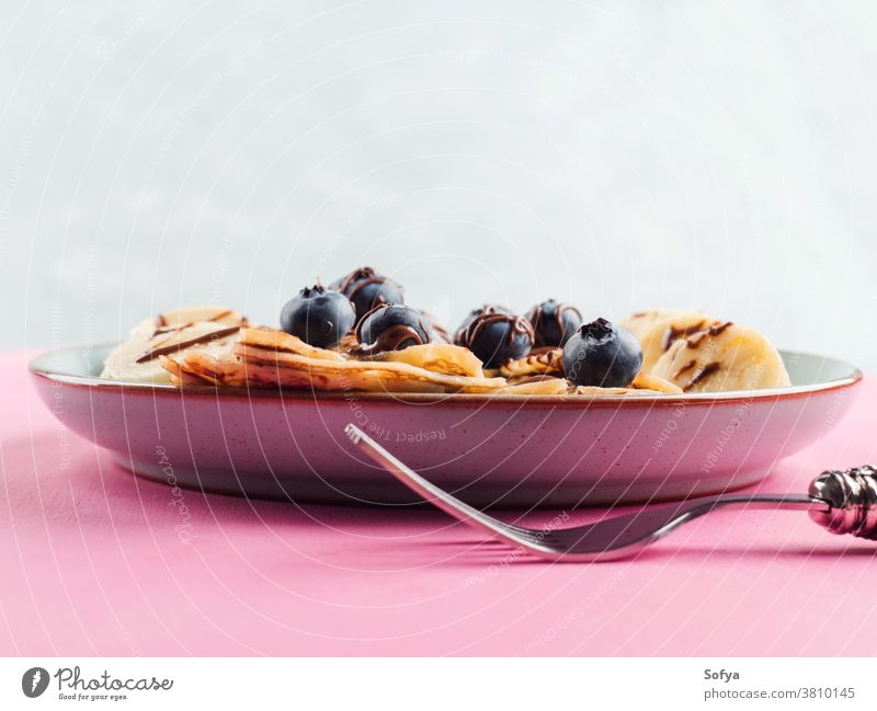 Eating crepes with chocolate and blueberries banana hazelnut fork chandeleur pink sweet breakfast closeup spread eat maslenitsa served pancake dessert