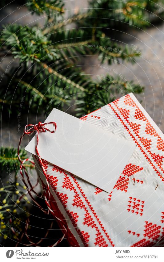 Wrapped christmas gift box, with empty tag and red tape, surrounded by pine branches on grunge blue background craft paper wrapped label rustic tradition loop