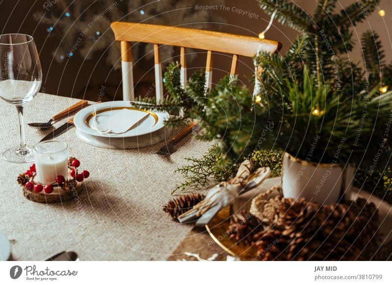 Cosily laid Christmas table, decorated with pine branches and rustic tablecloth in the living room with tree lighting Thanksgiving Table Set meal Menu Home Food