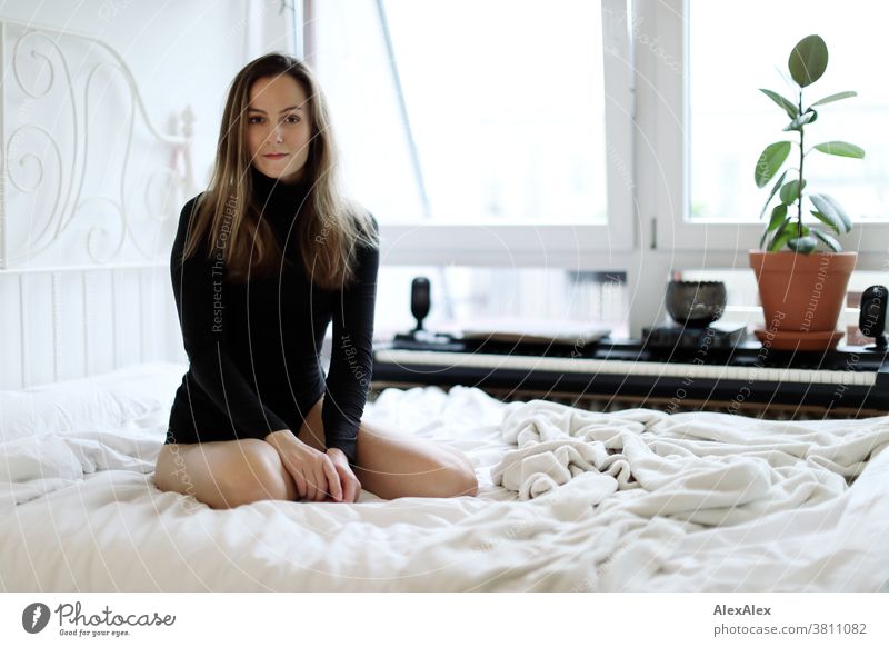 Close portrait of a young woman kneeling on a bed and looking into the camera Woman 18 - 30 years pretty fit Slim smart kind Pleasant Attractive Brunette