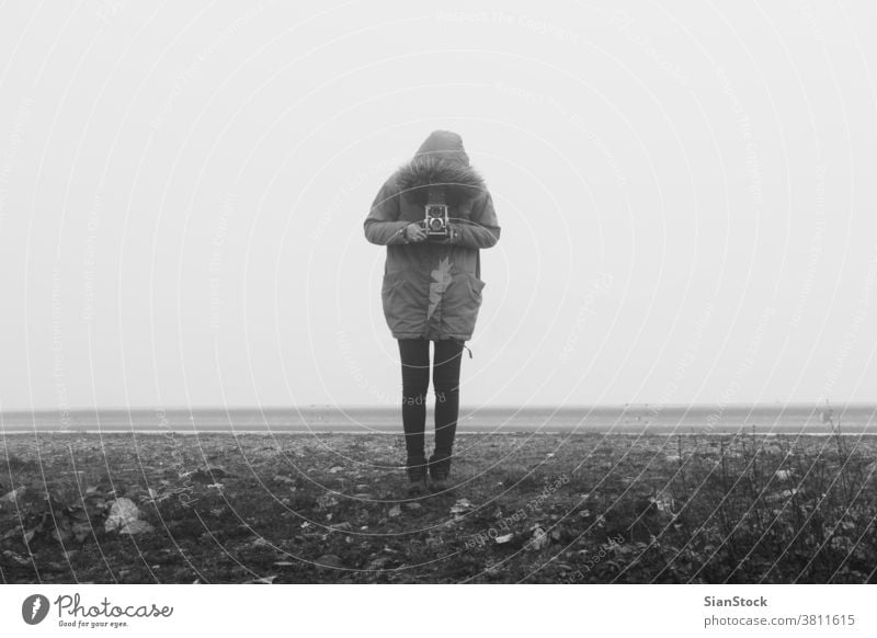 Woman with retro camera in a fog landscape misty black white b&w vintage winter art photo girl woman old taking person photographer holding photography outdoors